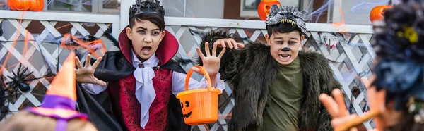 Asijské Děti Halloween Kostýmy Drží Kbelík Blízkosti Rozmazané Přátele Venku — Stock fotografie