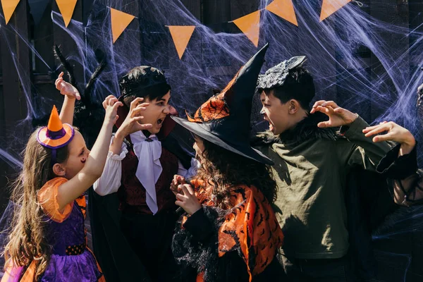 Mezirasové Děti Kostýmech Sebe Šklebí Halloweenské Výzdoby Dvorku — Stock fotografie