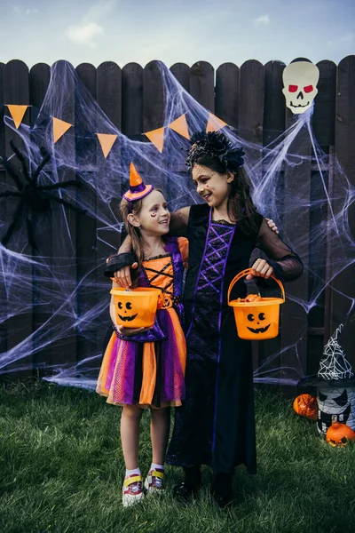 Smiling Preteen Kids Hugging Holding Halloween Buckets Backyard — Stock Photo, Image