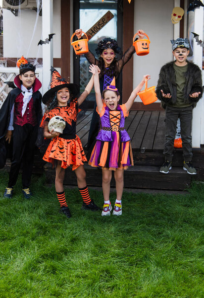 Cheerful interracial kids celebrating halloween during party in backyard