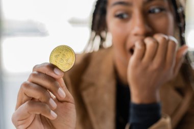 KYIV, UKRAINE - 27 Nisan 2022: Bitcoin tutan bulanık Afrikalı Amerikalı iş kadını 