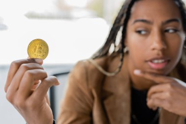 KYIV, UKRAINE - 27 Nisan 2022: Ofiste Bitcoin 'e bakan bulanık Afrikalı Amerikalı iş kadını 