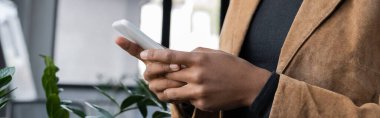 Afrika kökenli Amerikalı spor ceketli müdürün ofisinde akıllı telefon kullanması, afiş. 