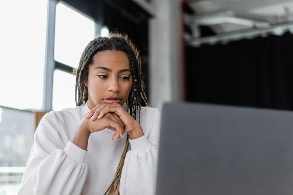 Εστιασμένη Αφροαμερικάνα Επιχειρηματίας Που Κοιτάζει Θολό Φορητό Υπολογιστή Στο Γραφείο — Φωτογραφία Αρχείου