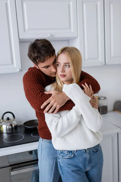 Jovem Homem Camisola Vermelha Abraçando Namorada Loira Cozinha — Fotografia de Stock