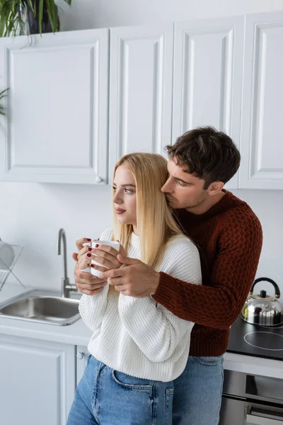 Hombre Joven Jersey Punto Abrazando Mujer Rubia Con Taza Durante — Foto de Stock