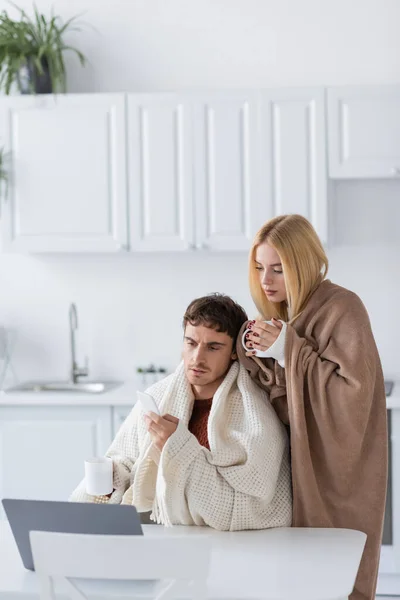 Mujer Rubia Cubierta Manta Taza Celebración Cerca Freelancer Con Teléfono —  Fotos de Stock