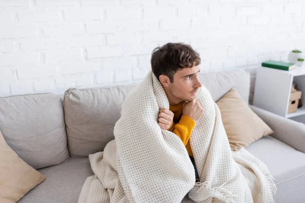 Joven Cubierto Manta Sentado Sofá Calentándose Sala Estar —  Fotos de Stock