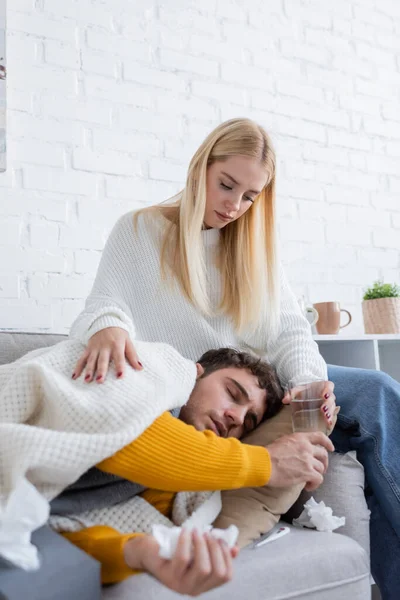 Caring Young Woman Sitting Sofa Giving Glass Water Sick Boyfriend — Stock Photo, Image