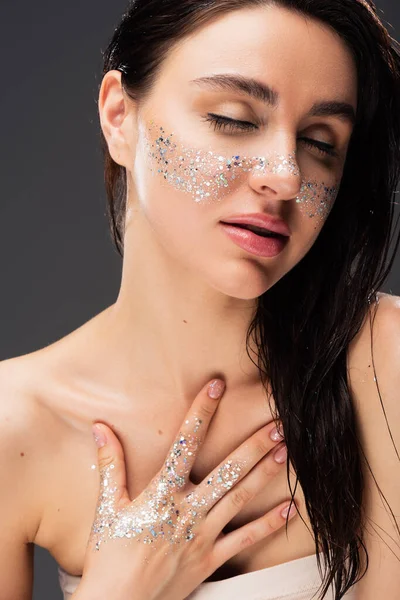Young Brunette Woman Sparkling Glitter Cheeks Hand Touching Chest Isolated — Stock Photo, Image