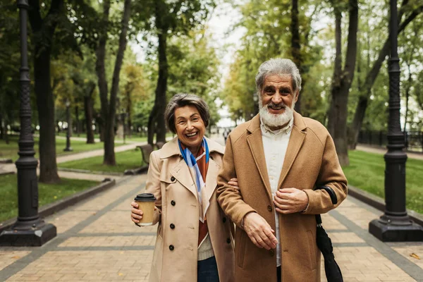 Glückliche Seniorin Mit Pappbecher Beim Spazierengehen Mit Stilvollem Mann Mantel — Stockfoto