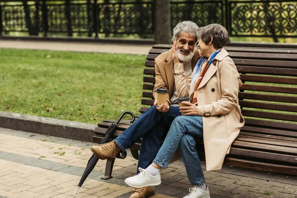 Cheerful Senior Couple Coats Holding Paper Cups Sitting Bench Park — Stock Photo, Image