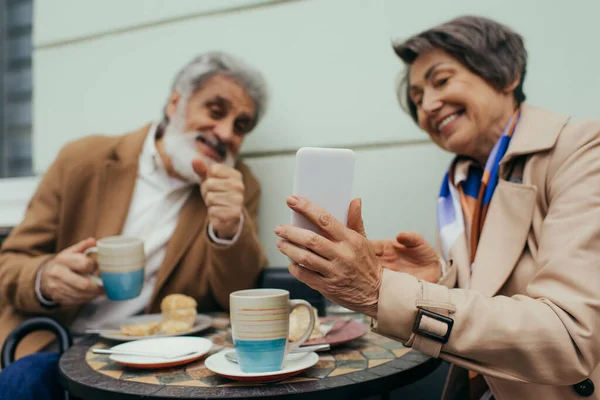 Счастливая Пожилая Женщина Держит Смартфон Время Завтрака Мужем Террасе Кафе — стоковое фото