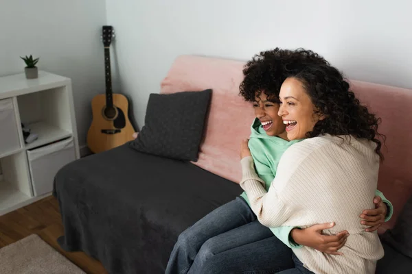 积极的非洲裔美国人母亲和女儿坐在沙发上拥抱 — 图库照片