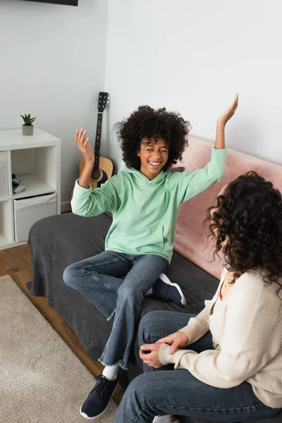 Feliz Afroamericano Chica Sonriendo Mientras Gesticulando Cerca Madre Rizada Sala —  Fotos de Stock