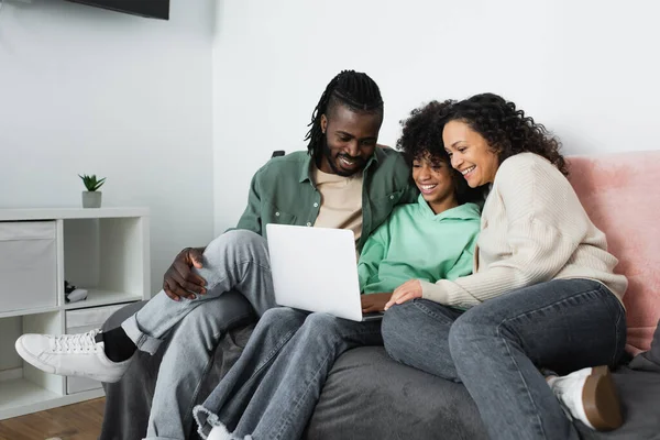 快乐的非洲裔美国家庭在客厅里用笔记本电脑看喜剧电影 — 图库照片