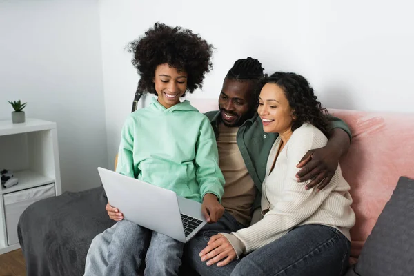 快乐的非洲裔美国家庭在客厅里用笔记本电脑看喜剧电影 — 图库照片