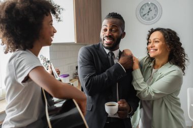 Mutlu Afrika kökenli Amerikalı genç kız pozitif ebeveynlerin yanında akustik gitar çalıyor. 