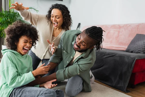 Vreugdevolle Afrikaanse Amerikaanse Vader Kietelen Tiener Dochter Buurt Gelukkig Vrouw — Stockfoto