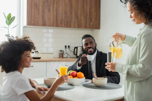 Alegre Afroamericano Hombre Negocios Traje Mirando Esposa Verter Jugo Naranja — Foto de Stock