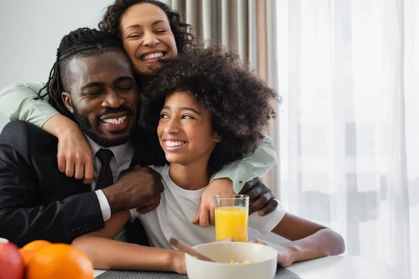 アフリカ系アメリカ人の幸せな家族が家で朝食中に抱きつき — ストック写真