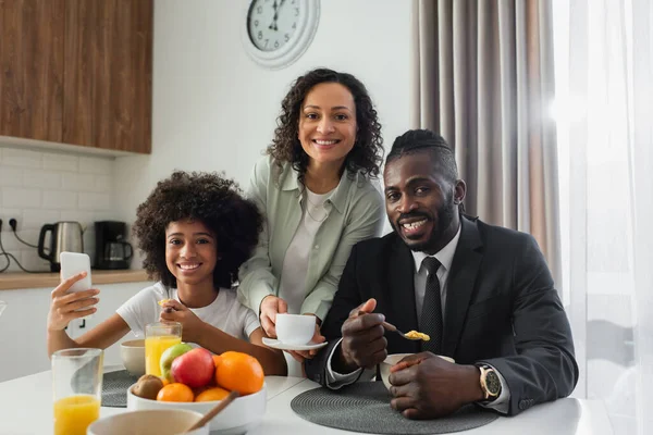 明るいアフリカ系アメリカ人女性がスーツ姿で夫の近くにコーヒーカップを持っていて — ストック写真