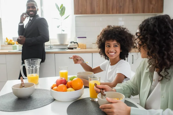幸せなアフリカ系アメリカ人の母親と娘はビジネスマンの近くで朝食をとり — ストック写真