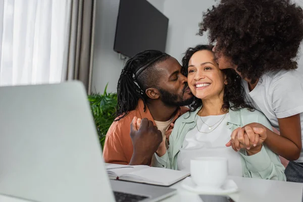非洲裔美国男子和少女在书桌上的笔记本电脑前亲吻快乐的女人 — 图库照片