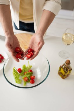 Kesilmiş adamın elinde salata ve yağ şişesiyle kasenin yanında kiraz domatesleri tuttuğu en iyi manzara.