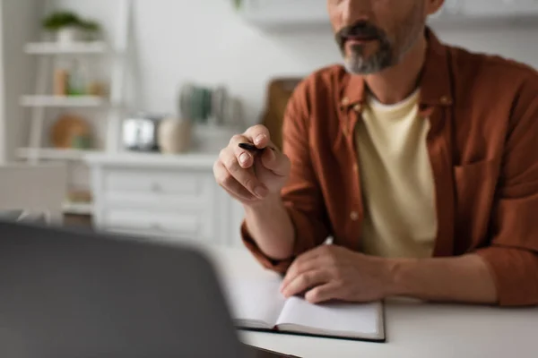 Mutfakta Çalışan Adamın Kırpılmış Görüntüsü Bulanık Dizüstü Bilgisayara Kalemle Işaret — Stok fotoğraf