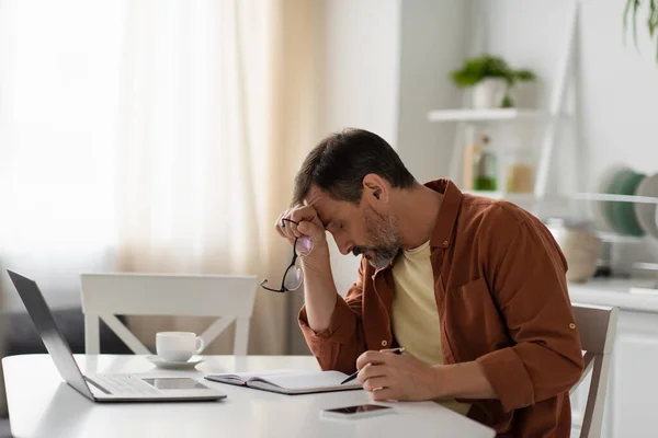 Hombre Agotado Sentado Con Cabeza Inclinada Cerca Los Dispositivos Portátil — Foto de Stock