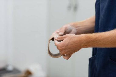 Çömlekçilik dersinde kil parçasını ellerinin arasında daire içine alan insan görüntüsü.