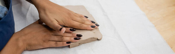 cropped view of african american woman shaping clay piece with hands during pottery class, banner