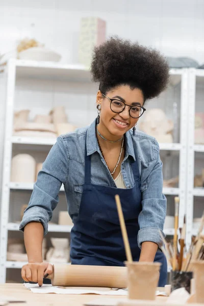 戴眼镜的快乐的非洲裔美国女人 带着滚动销的围裙造型黏土 — 图库照片