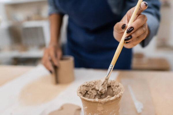 cropped view of african american woman holding focused clay shaper 