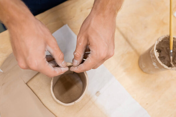 top view of man modeling clay piece in circle shape during pottery class 