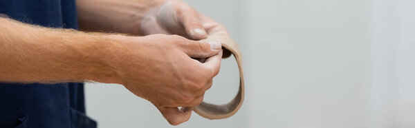 cropped view of man shaping clay piece into circle in hands during pottery class, banner