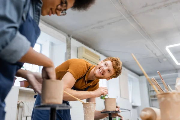 Hombre Sonriente Mirando Borrosa Novia Afroamericana Cerca Arcilla Estudio Cerámica — Foto de Stock