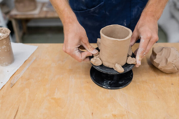 Cropped view of craftsman making ceramic sculpture in pottery workshop 