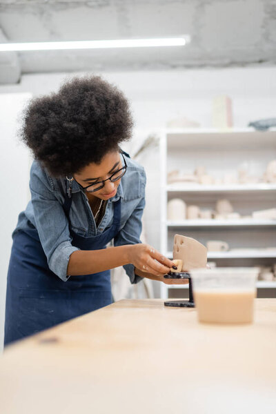 African american craftswoman making ceramic sculpture with sponge in pottery studio 