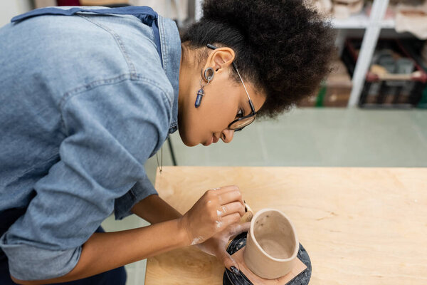 Side view of african american artisan forming ceramic product in pottery studio 