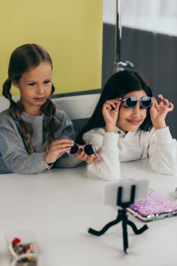 Ergen blogcular akıllı telefonun yanında şık güneş gözlüğü gösteriyorlar.