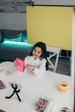 Evde sarı arka plan üzerine video blogu kaydederken elinde kalem kılıfı tutarken mutlu esmer.