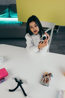 Boncuklu bilezikler ve bulanık cep telefonu yanında moda güneş gözlüğü gösteren genç bir kız.