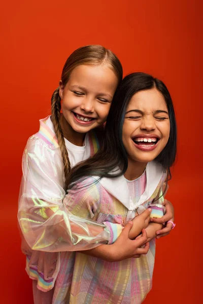 Overjoyed Girls Hugging Laughing Closed Eyes Isolated Orange — Stock Photo, Image