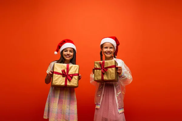 Happy Friends Santa Hats Smiling Camera While Holding Gift Boxes — Stock Photo, Image
