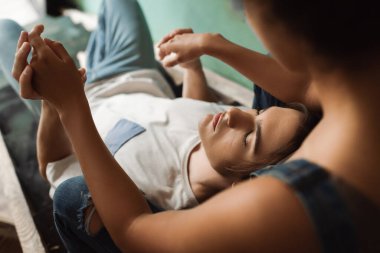 Sanat atölyesinde gözleri kapalı bir adamın elini tutan bulanık Afrikalı Amerikalı kadının yüksek açılı görüntüsü