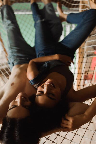 top view of happy multiethnic artists lying in mesh hammock above art studio