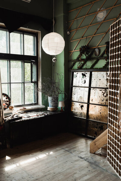 art workshop with large window and decorative lattice near vintage glass under sphere chandelier