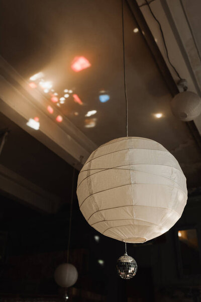 white handmade sphere chandelier with small disco ball and rays of light on ceiling in art studio